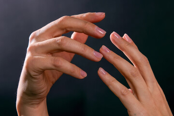 Female hands illuminated by light on dark background