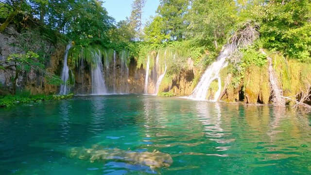 Plitvice lakes and waterfalls, Croatia. View from tourist perspective. Walking near lake and waterfall in pure fresh nature. National nature park, famous travel destination.