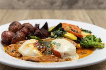 Veal escalope drenched in tomato sauce served with roasted vegetables and seasoned potatoes for a delicious dinner