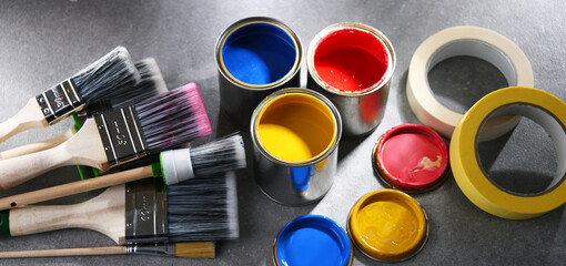 Paintbrushes of different size and paint cans
