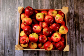 Red apples in a wooden box on a  wooden board background. Copy space 