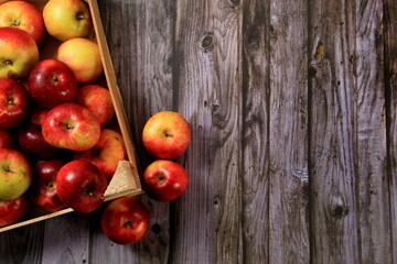 Obraz na płótnie Canvas Red apples in a wooden box on a wooden board background. Copy space 