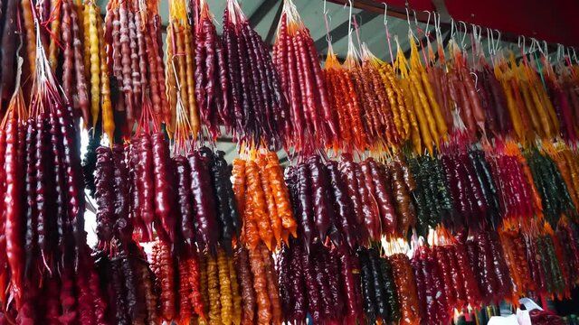 multicolored churchkhela hangs in East Street market. Traditional Georgian food is sweets in form of sausage. main ingredients are grape must, nuts and flour. Sale of sweets at bazaar.
