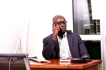 Confident adult business man talking on mobile phone in office.