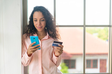 beautiful latin woman using smartphone with credit card