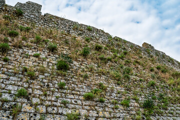 Rozafa Castle wall overgrown with plants (Shkoder, Albania), close-up. Abstract architectural background. Visual deception