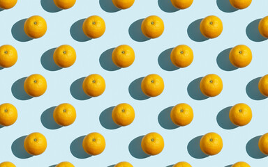 Seamless fruit pattern of fresh orange slices on blue background. Top view. Copy Space. Pop art design, creative summer concept. Half of citrus in minimal flat lay style.