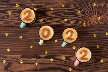 Symbol of New Year 2022 in four coffee cups with digits on a brown wooden background. Numbers on cappucino.