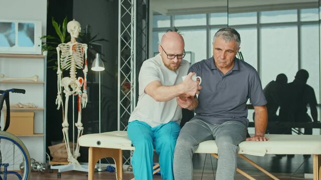 The Doctor Conducts a Physiotherapy Session with an Older Man With a Brain Stroke at the Modern Rehabilitation Clinic. The Affected Nervous System, Paralysis. Health Care Concept.