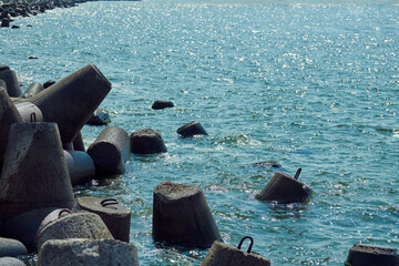 Large concrete breakwaters tetrapods near sea, close up. Blocks and stones, beautiful seascape