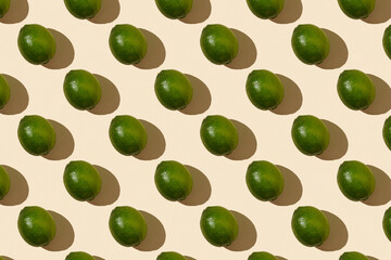 Trendy sunlight summer pattern made with green lime on bright light yellow background. Minimal summer concept. Flat lay.