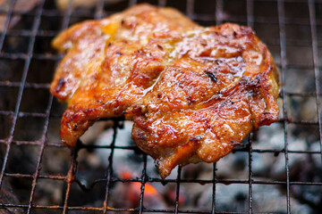 Pork steak being grilled on the charcoal stove