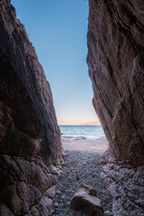 View between two rocky cliff walls of the secluded beach of Ficaghiola and turquoise Mediterranean sea on the west coast of Corsica