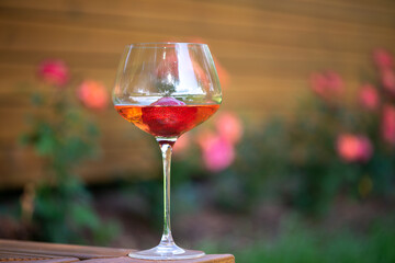A glass of chilled cold white wine with strawberries on an outdoor wooden terrace