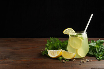 Lemonade or mojito cocktail with lemon and mint, cold refreshing drink or beverage with ice on rustic wood background. Homemade lemon and ginger organic drink, copy space.