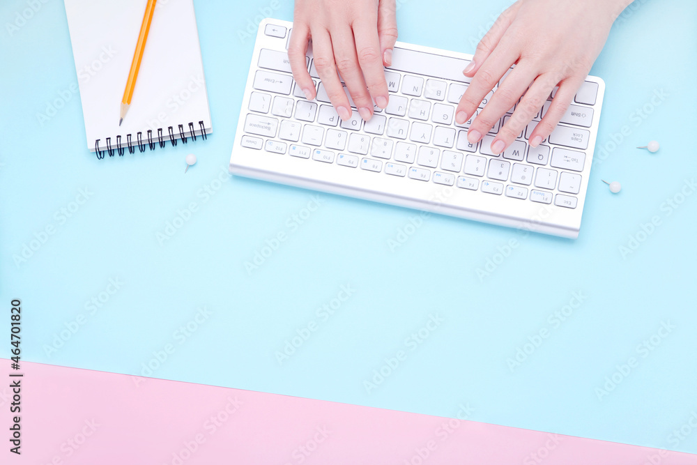Poster female hands typing on computer keyboard with notepad and pencil