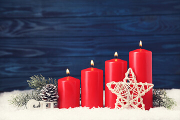 Christmas candles with star, wooden sleigh and fir tree branches on blue background