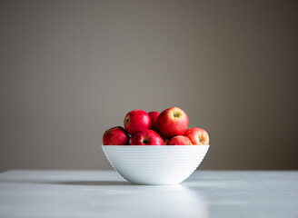 red apples in a white bowl isolated on a gray background