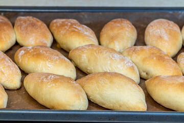 Fresh homemade pies, golden brown, fresh from the oven, are on a baking sheet.