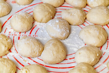 Balls of dough for homemade pies are prepared for rolling out on the table.
