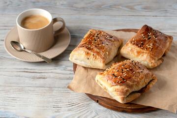 Samsa are Uzbek pies made of puff or plain dough stuffed with meat and onions. Real Uzbek samsa comes from oriental cuisine. Made from lamb and beef. Selective focus. Cup of coffee for breakfast.