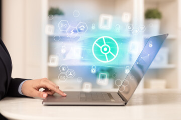 Hands working on laptop with digital icons