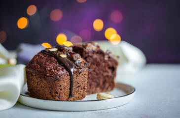 Close up of sliced vegan baked chocolate banana pie with chocolate topping on a white plate with christmas lights on a dark purple background
