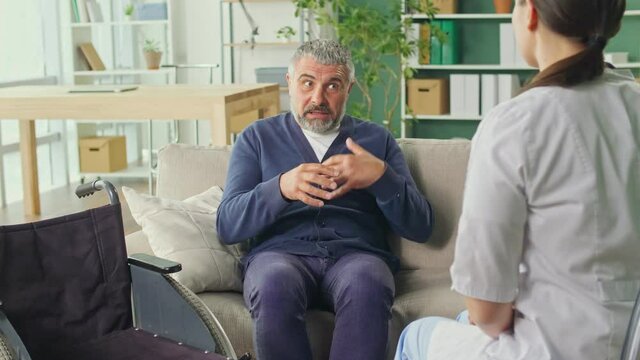 A Friendly Medical Professional Takes Care of a Middle-aged Man at Home. Medical Services, Rehabilitation, Consultation of a Medical Worker at Home. Pension Insurance and Health Care Concept.