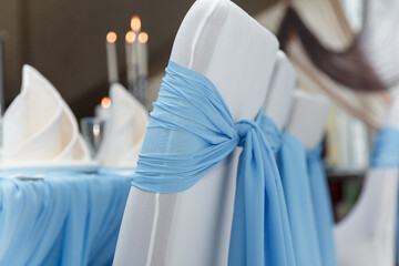 Beautiful blue and white wedding presidium, arm-chairs with decorative fabric, close up shot, candle lights bokeh on background
