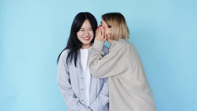 Woman gossip. Secret share. Female friendship. People diversity. Multiracial girls friends whispering rumor hearsay laughing on blue free space background.