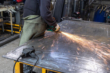 Bright sparks fly over the work table when grinding metal