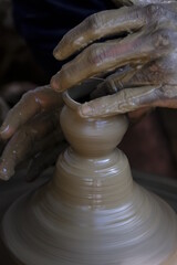 A potter prepares clay Pots or diya on potter's wheel in his residence ahead of Diwali festival. Wet and muddy hands of a craftsman shaping a clay vase on a pottery wheel.