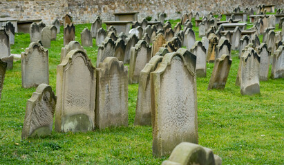  Close and selective focus on an old headstone, dating back to the 1800s, in a graveyard with the...