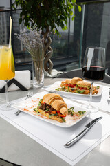 Two kinds of croissant sandwich with meat, tomatoes and lettuce salad and avocado on bright background. Continental style breakfast.