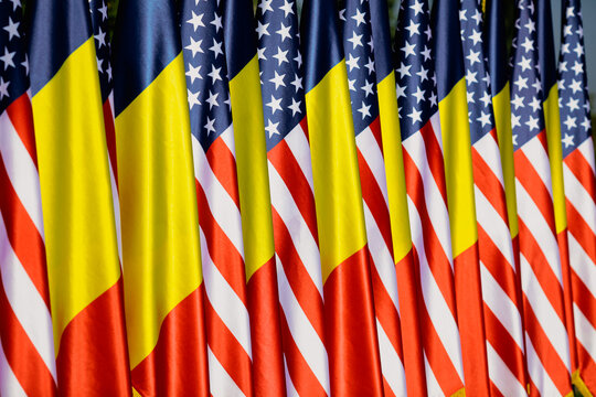 United States and Romanian flags on poles one next to another.