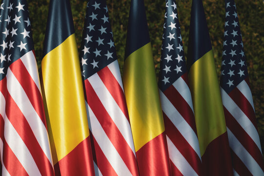 United States and Romanian flags on poles one next to another.