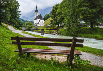 A wood bench with parish church, river abd mountains in background. berchtesgaden, Ramsau Germany