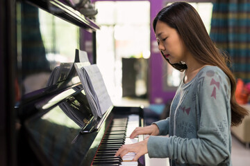 Young Asian woman play classic Piano at home