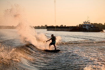 view of energy athletic male wakeboarder riding water and a lot of splashes behind him