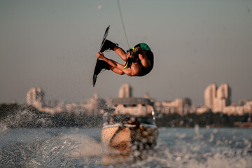 energy man skilfully jumping and flips on wakeboard over splashing wave
