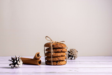 Cookies with pieces of chocolate , cinnamon and fir cones on a light background