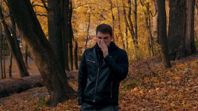 Young man farted in autumn forest. Relaxed male felt stink, looks around and leaves. Slow motion.
