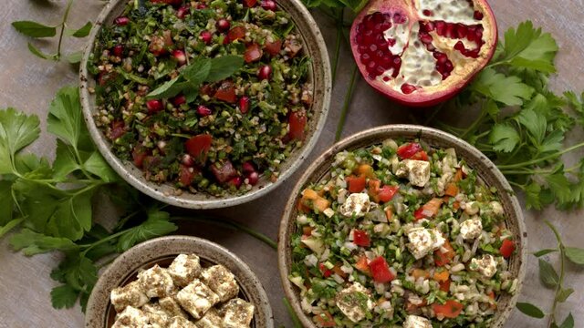 Typical Tabbouleh salad with parsley and other tabbouleh style salad with barley and feta. Top view, table spin.