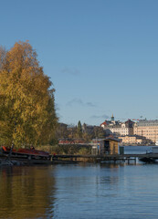 Fototapeta na wymiar Piers with boats at the islands in the Stockholm harbor a colorful autumn day