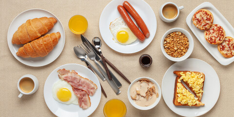 Hearty homemade family breakfast. Eggs, bacon, sausages, beans, croissants, toast and coffee on the table. Top View