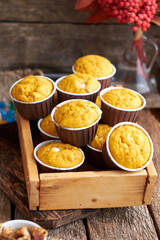 Pumpkin muffins with white chocolate and walnuts. Side view, wooden background.