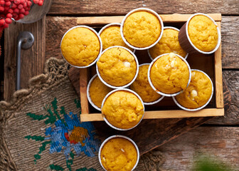 Pumpkin muffins with white chocolate and walnuts. Side view, wooden background.