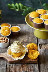 Pumpkin muffins and cupcake with white chocolate and walnuts. Side view, wooden and green background.