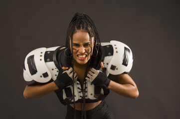 young woman with american football shoulder pads, ball, and aggressive face, half body
