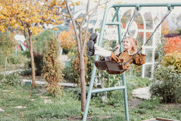 happy little girl laughing and swinging on a swing in autumn in nature, walking in nature